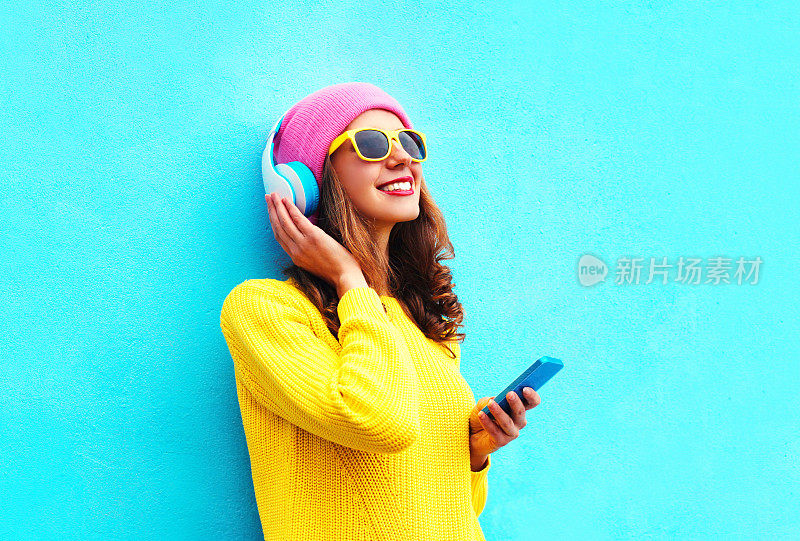 时尚女孩用智能手机耳机听音乐，色彩缤纷