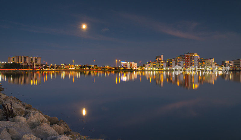 月亮和城市风景的灯光，反射海港水域，普尔