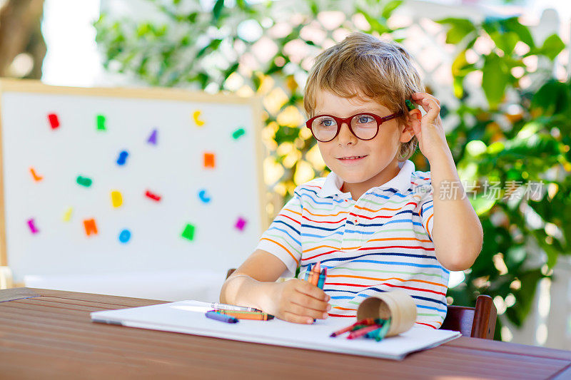 一个戴眼镜拿着蜡笔的小男孩