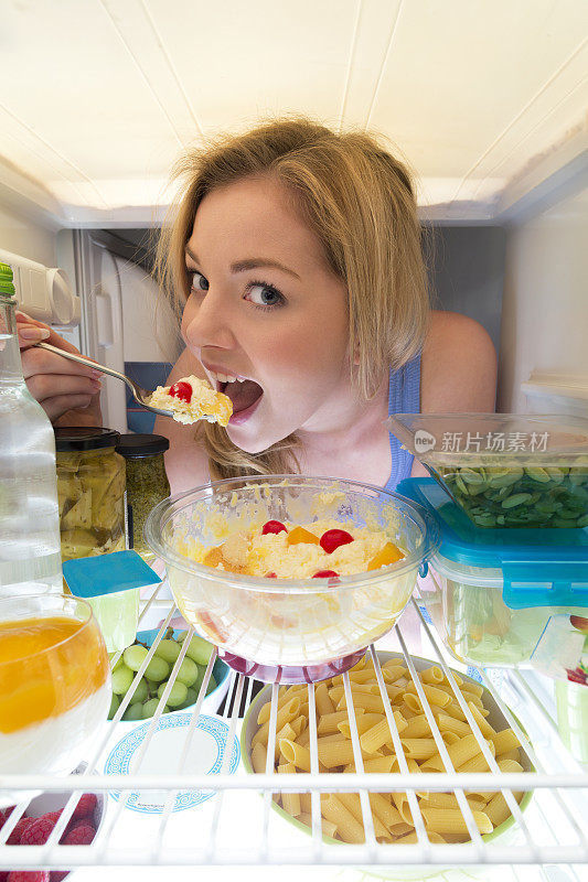 年轻女子用冰箱吃东西