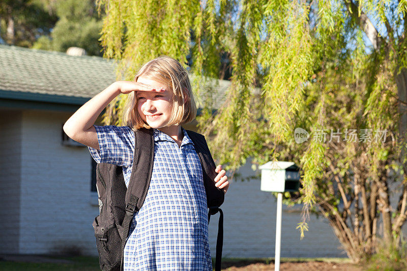 穿着校服的小女生在屋外等公车