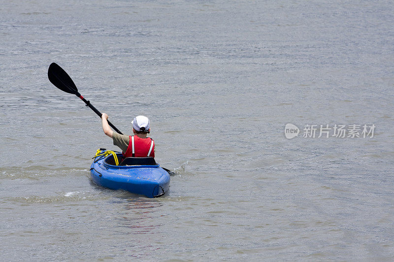 小男孩在水上划着皮划艇