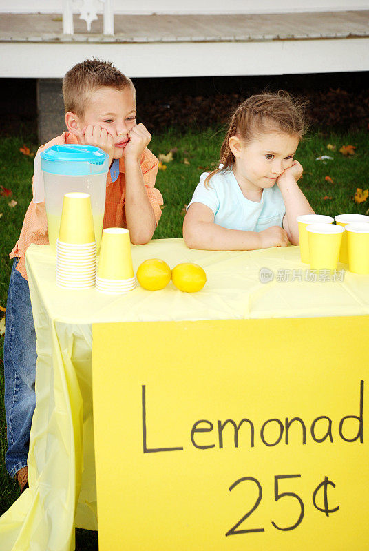 无聊的小男孩和小女孩站在柠檬水摊后面