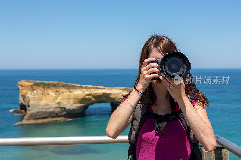 女摄影师在海滩上用单反相机拍照
