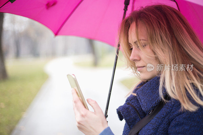 年轻女子与手机在雨天