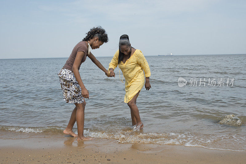 两个非洲裔美国妇女在海滩上涉水