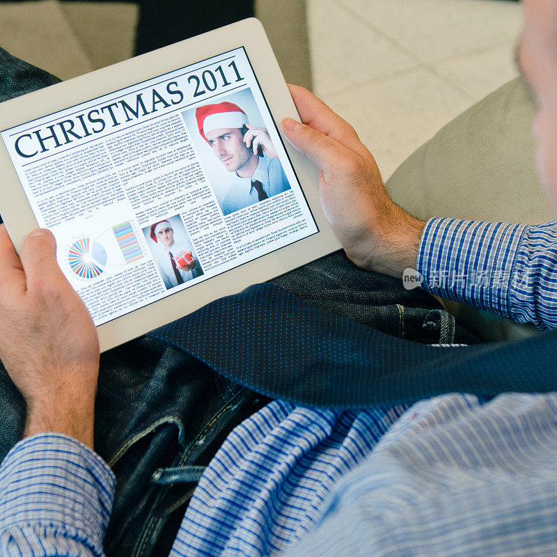 一个拿着电子平板电脑和圣诞报纸的男人