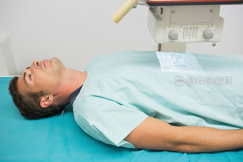 男病人躺在检查台上接受放射检查