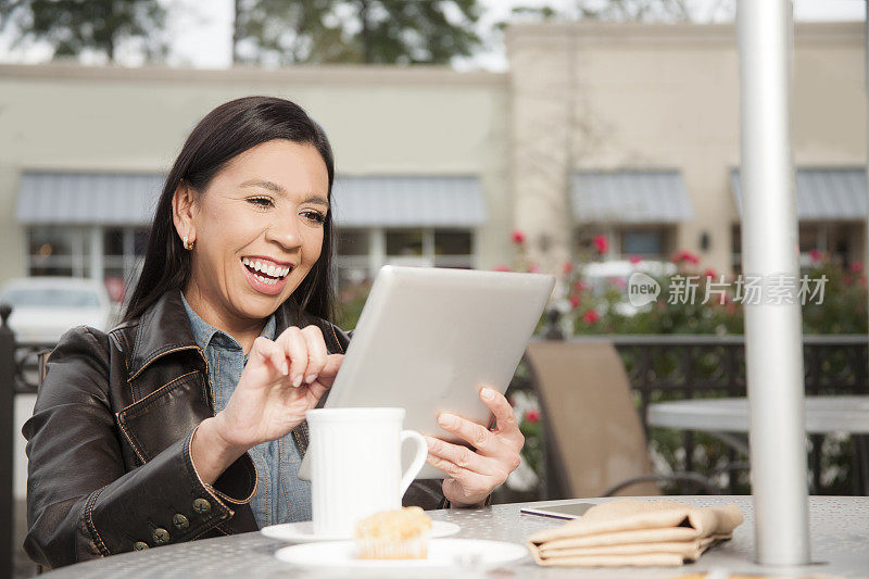 在户外咖啡店里使用平板电脑的女人。