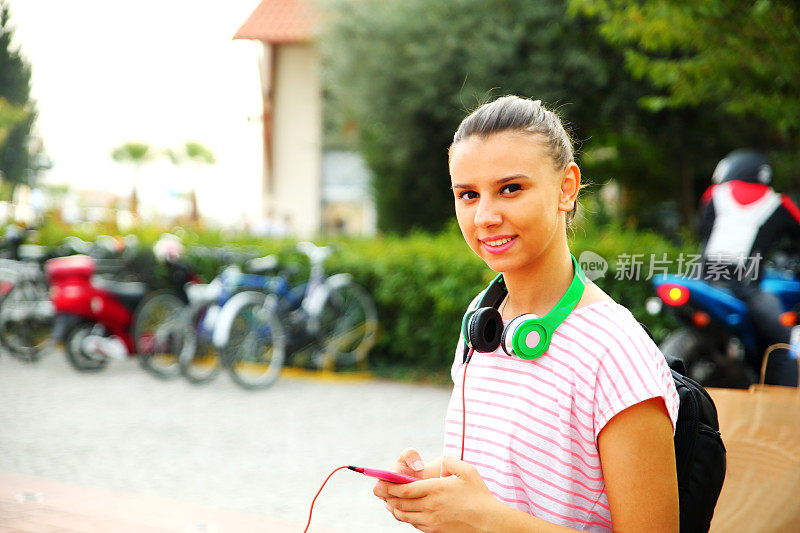 一个女孩在校园里戴着耳机听音乐