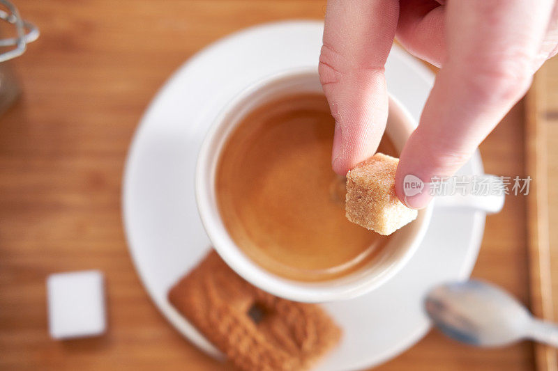 手和方糖放在咖啡杯上