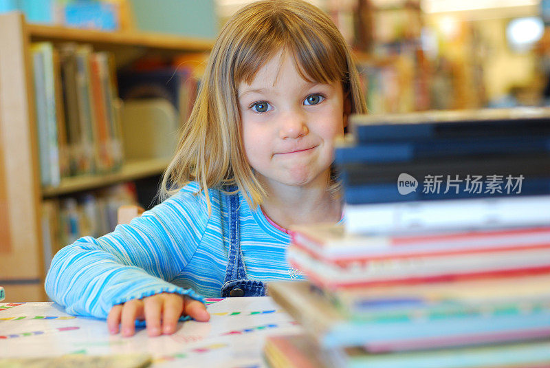 小女孩和成堆的书在图书馆