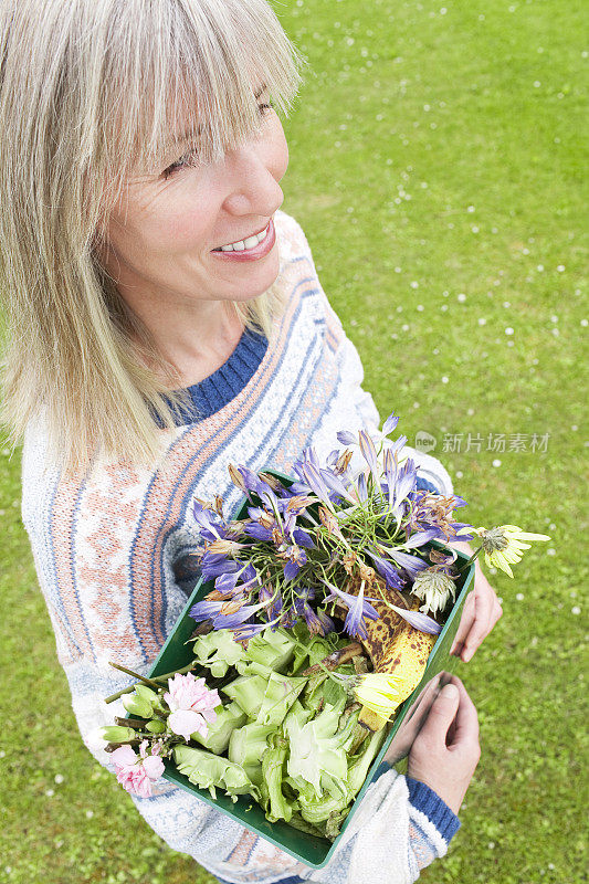 女人拿着凋谢的花去做堆肥