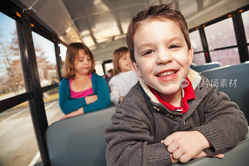 快乐的小男孩和其他学生坐在校车上