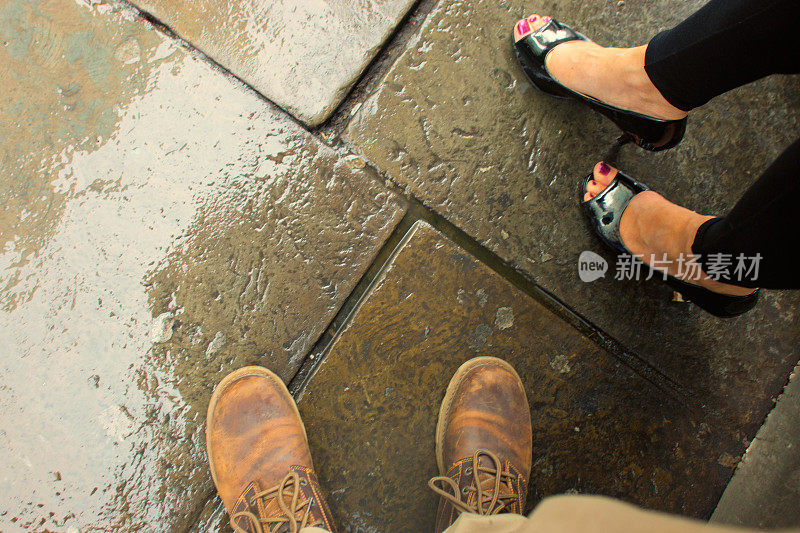一对情侣的脚在雨中等待