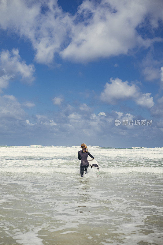 男冲浪者涉水进入大海，陶万海滩，纽基，康沃尔
