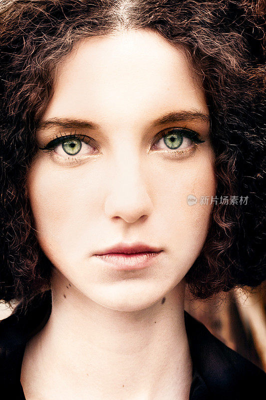 肖像的年轻卷发女人与大绿色眼睛