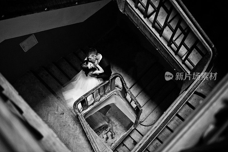 一对新婚夫妇站在一所老房子入口处的木楼梯上