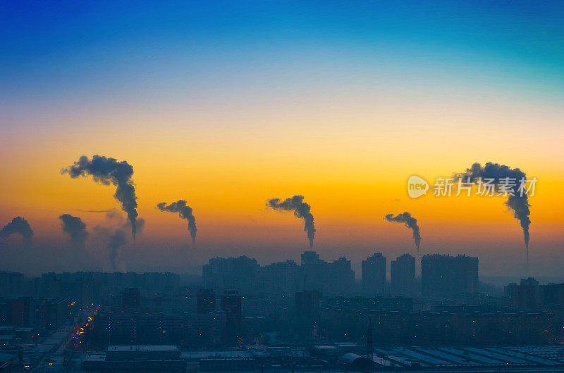 傍晚的城市工业景观与烟气排放的烟囱在日落