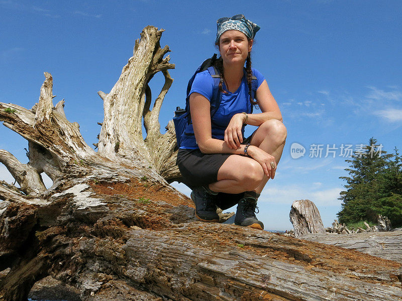 女性徒步旅行者蹲在浮木旁边