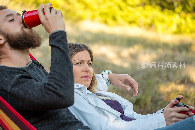 年轻的男孩和女孩在美丽的森林后面的橙色吊床上