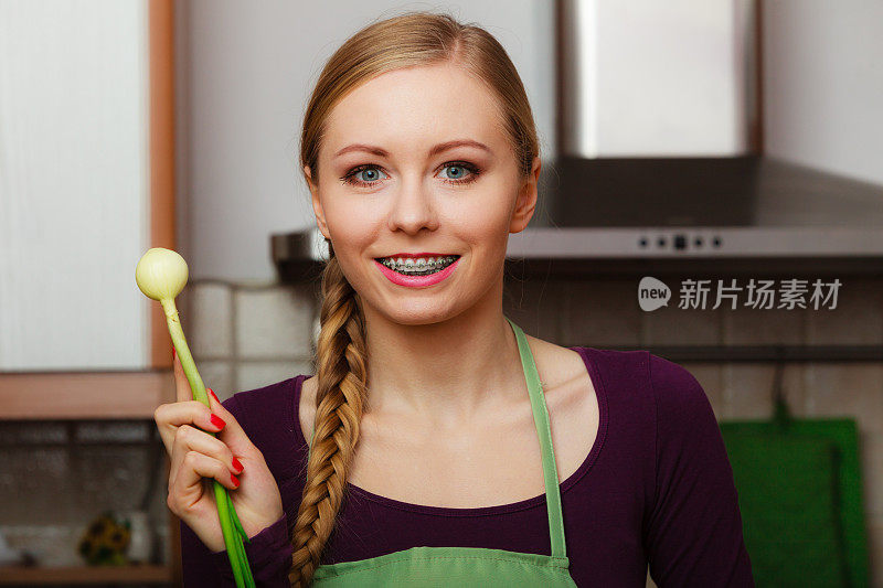 厨房里的女人拿着新鲜的绿韭菜