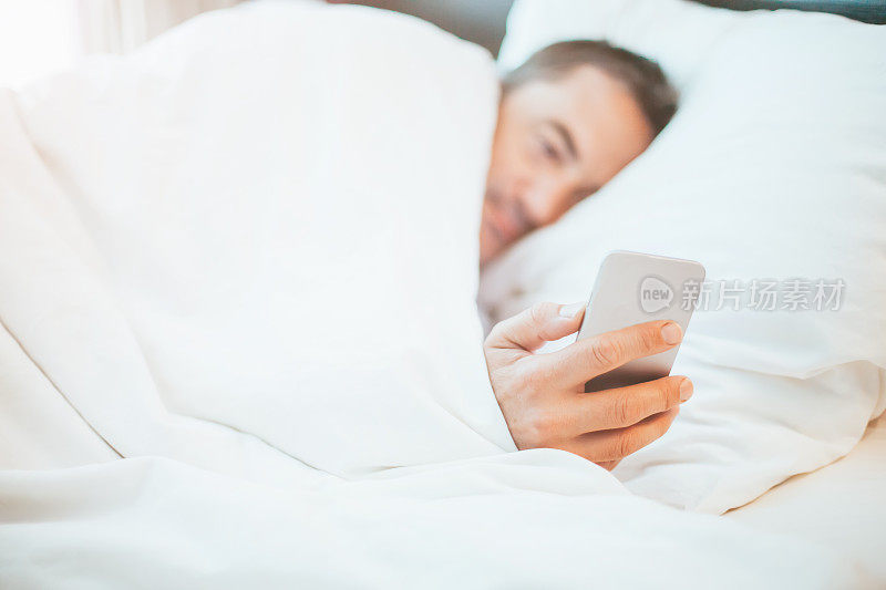 男人在床上使用智能手机
