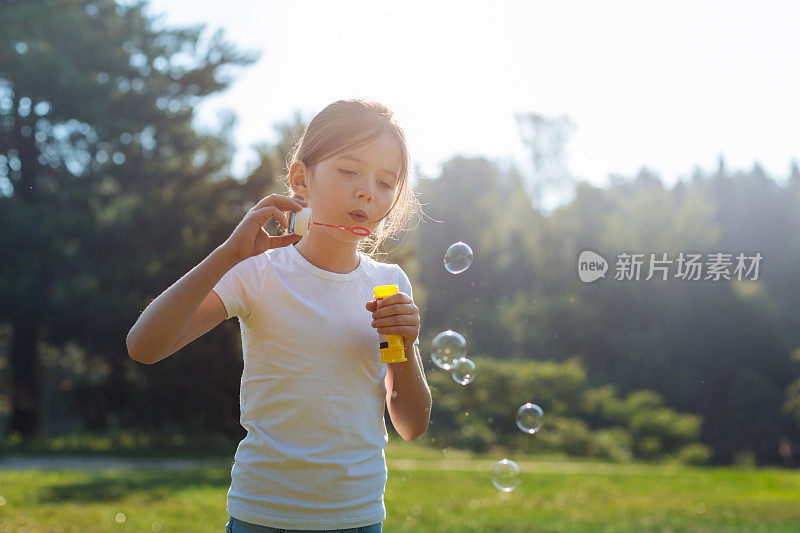 可爱的小女孩在公园里吹肥皂泡