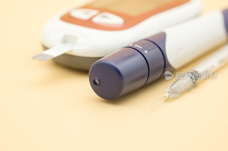胰岛素注射器和血糖仪的关闭与柳叶刀检查血糖水平橙色背景作为药物，糖尿病，血糖，保健和人的概念