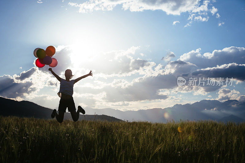欢呼的年轻女子在草地上跳彩色气球