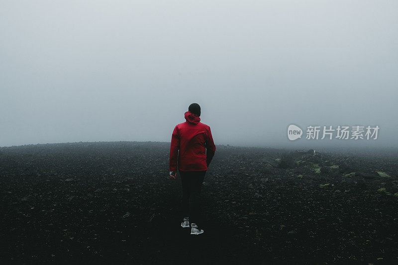 穿着红色夹克的人徒步穿越冰岛的火山景观和风