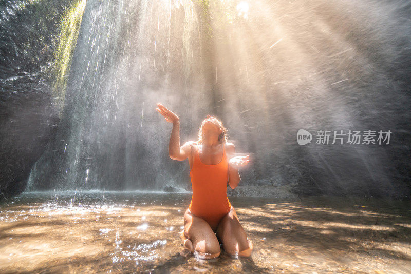 热带雨林里的年轻女子仰望着美丽的阳光用手触摸着雨滴。人们旅游是享受自然和生活的理念