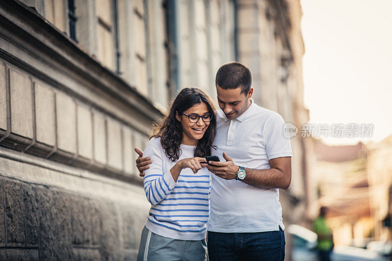 幸福的夫妇在街上用手机