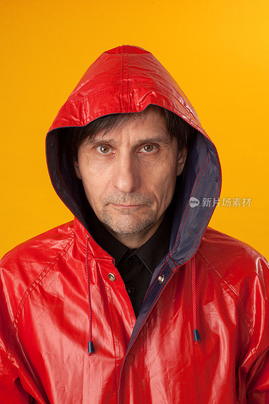 一个穿着红色雨衣，黄色背景的男人的工作室肖像
