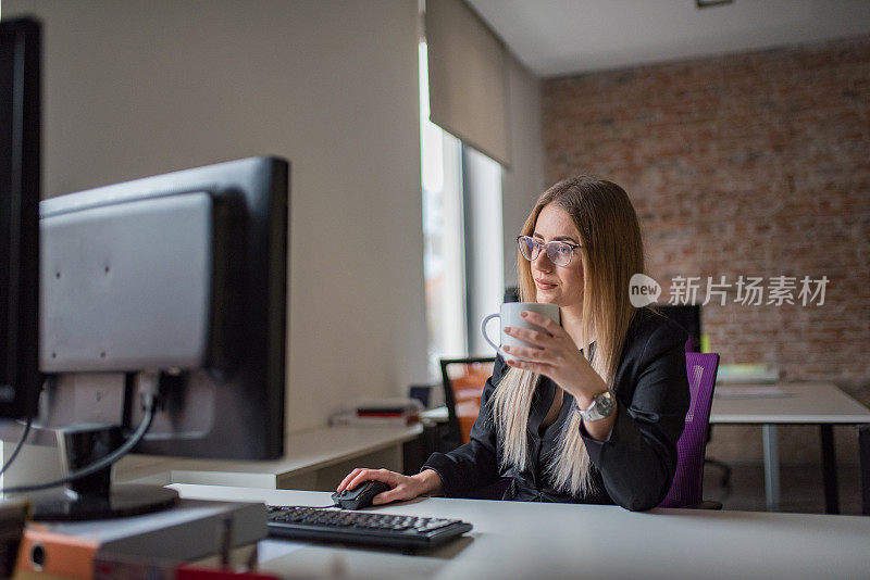 女商人用电脑，在办公桌前喝咖啡