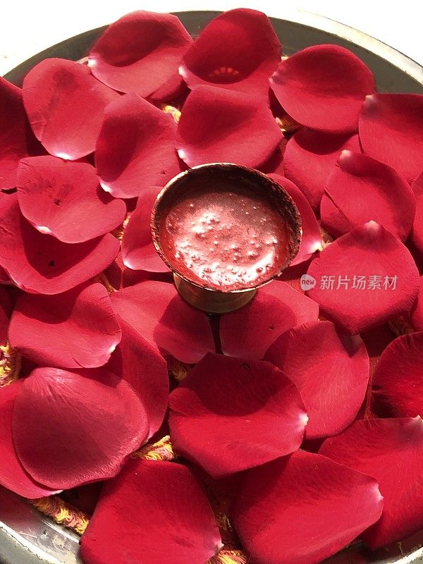 印度提拉克问候的图像，芳香的印度提拉卡膏与檀香和红玫瑰花瓣在托盘上，准备在印度宗教仪式上标记前额