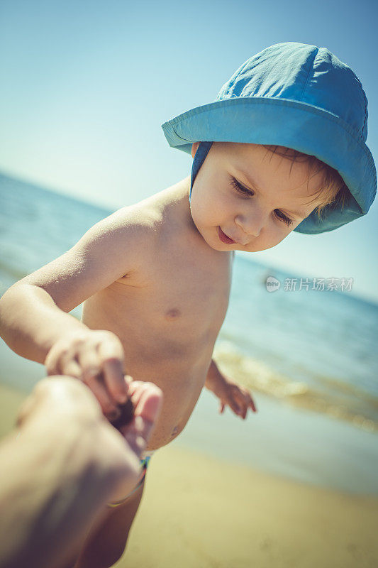 可爱的小男孩在海滩上玩贝壳和石头