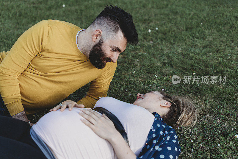 一对年轻的夫妇躺在草地上。他们一起等待着孩子的出生。