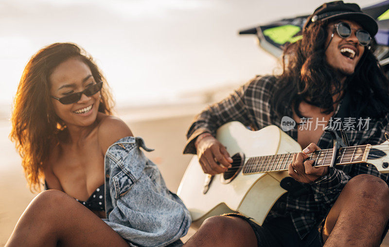 一个家伙在海滩上给一个女人弹原声吉他