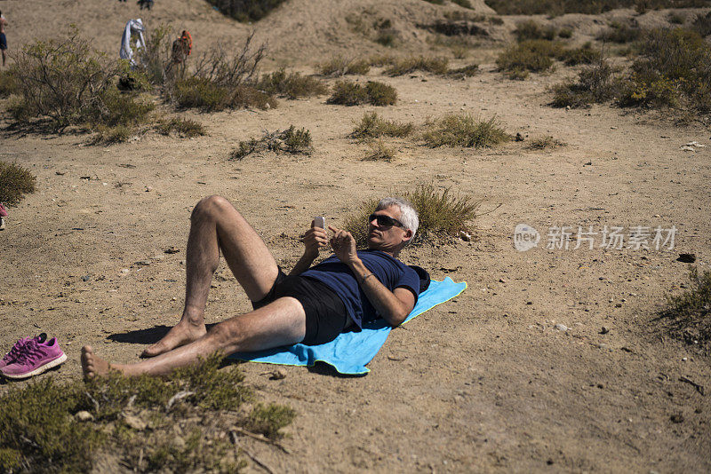 吉尔吉斯斯坦，游客在伊塞克-库尔盐湖上进行泥巴疗法后，在阳光下放松