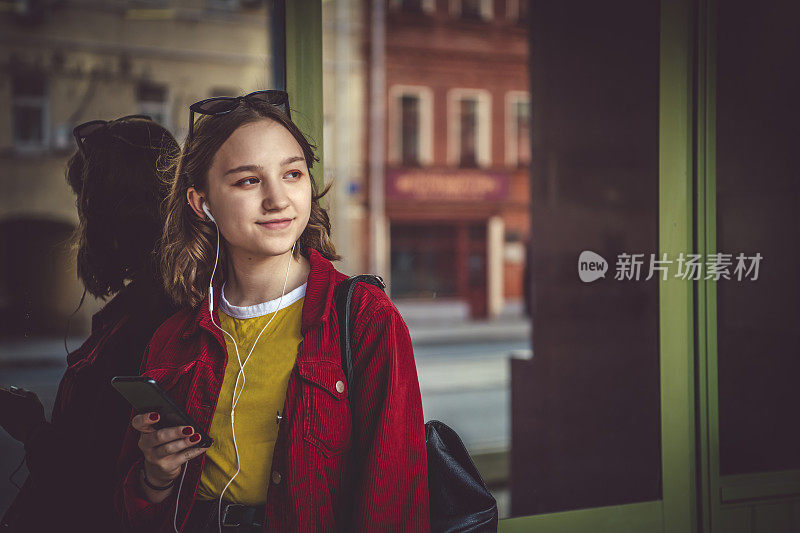 夏天，少女在街上用智能手机听音乐