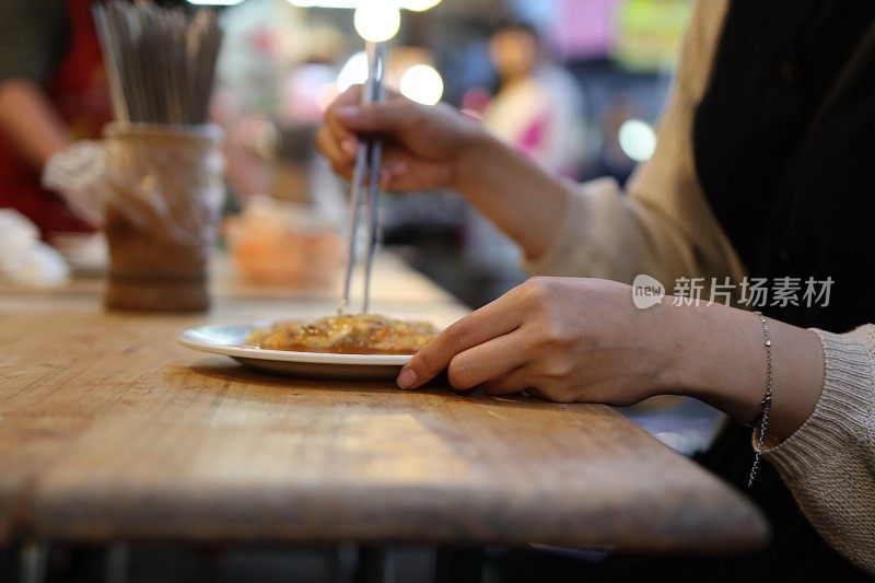 年轻女子在夜市享受美食