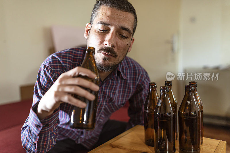 年轻悲伤的醉酒男子喝啤酒和酒精感到浪费，孤独和绝望的痛苦和情绪压力。人与酗酒、上瘾和男人抑郁的概念。