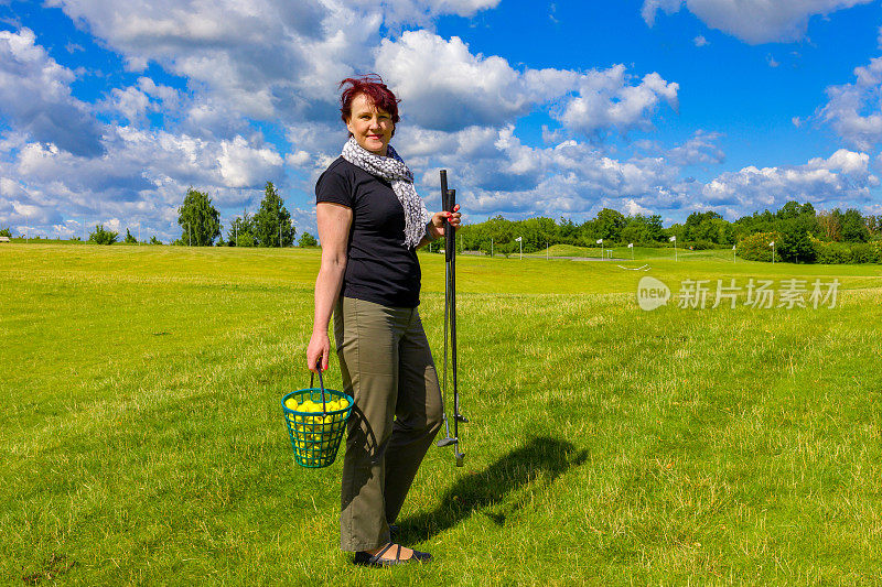 女人拿着一个篮子，里面装着高尔夫球和高尔夫球杆
