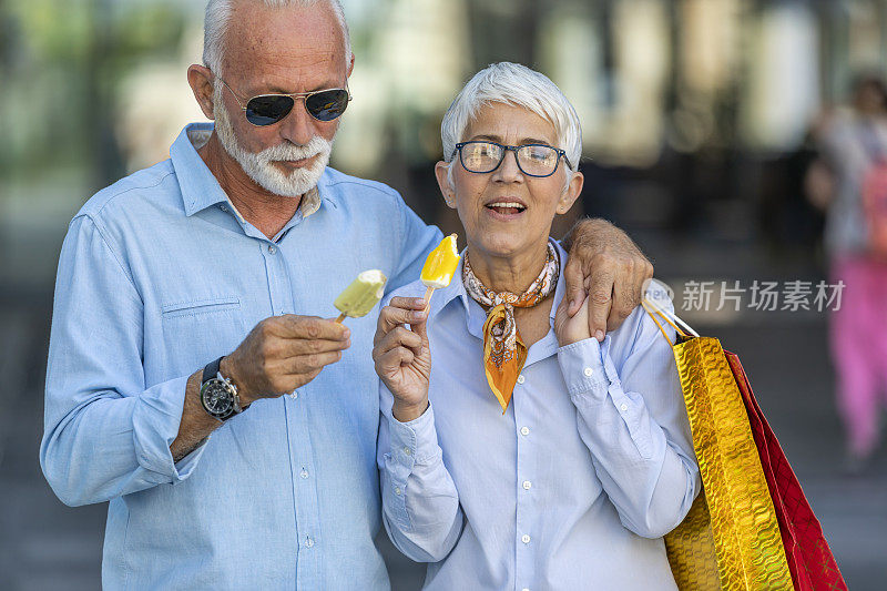 一对活跃的老年夫妇在购物中心购物成功后享用冰淇淋