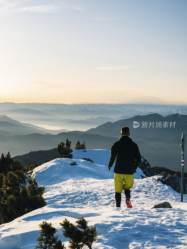 黎明时分，一名徒步运动员爬上雪山的山脊