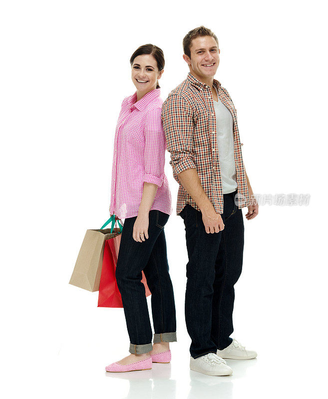 白人年轻男子购物狂穿着牛仔裤，拿着购物袋站在白色背景前