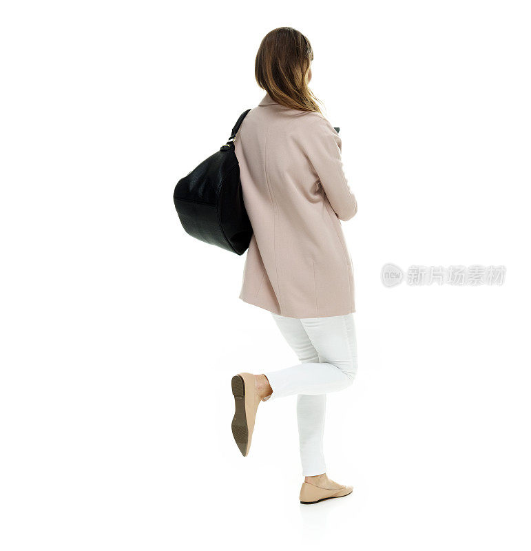 白人年轻女性穿着运动夹克，拿着钱包走在白色背景前