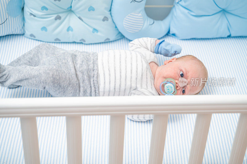 婴儿躺在他的婴儿床上，吸着奶嘴