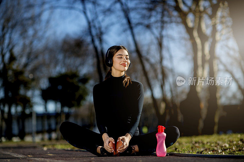 年轻的女运动员在慢跑和听音乐后放松